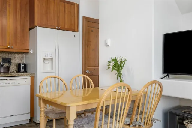 a dining room with furniture a potted plant and a kitchen view