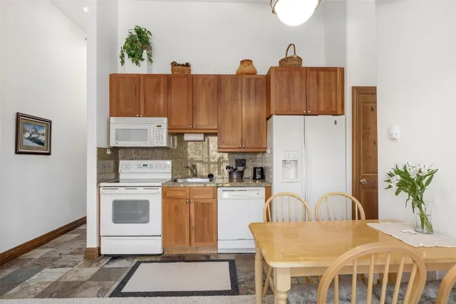 a kitchen with stainless steel appliances a stove a refrigerator a table and chairs