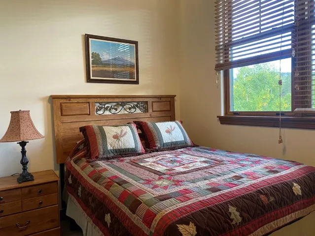 a bedroom with a bed and a lamp on dresser