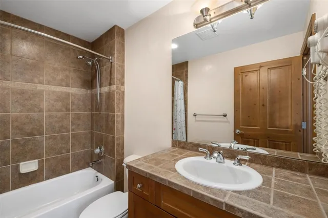 a bathroom with a granite countertop sink a mirror a bathtub and shower