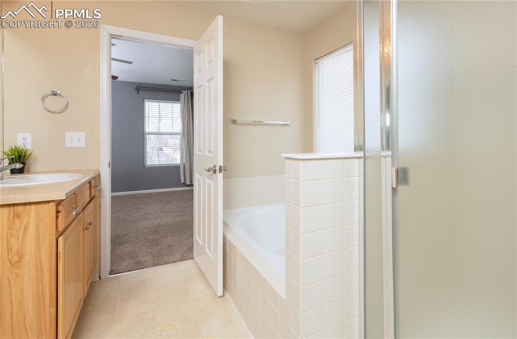 4815 Harrier Ridge Drive Colorado Springs, CO 80916 - Photo 14 of 33 Bathroom with vanity, a stall shower, a garden tub, and light tile patterned floors