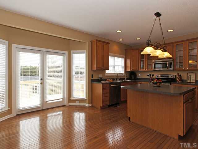 740 Rockville Road Wake Forest, NC 27587 - Photo 6 of 25 a kitchen with stainless steel appliances granite countertop a stove a sink a refrigerator and a dining table with wooden floor