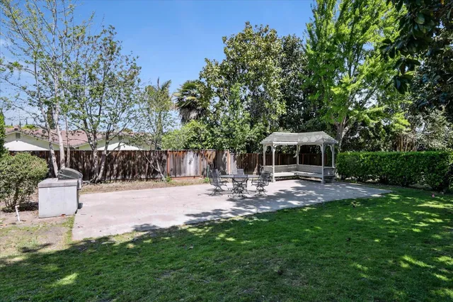 a view of a patio with table and chairs potted plants and large tree