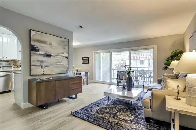 a living room with furniture large window and wooden floor