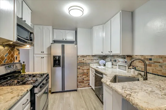 a kitchen with stainless steel appliances granite countertop a sink stove and refrigerator
