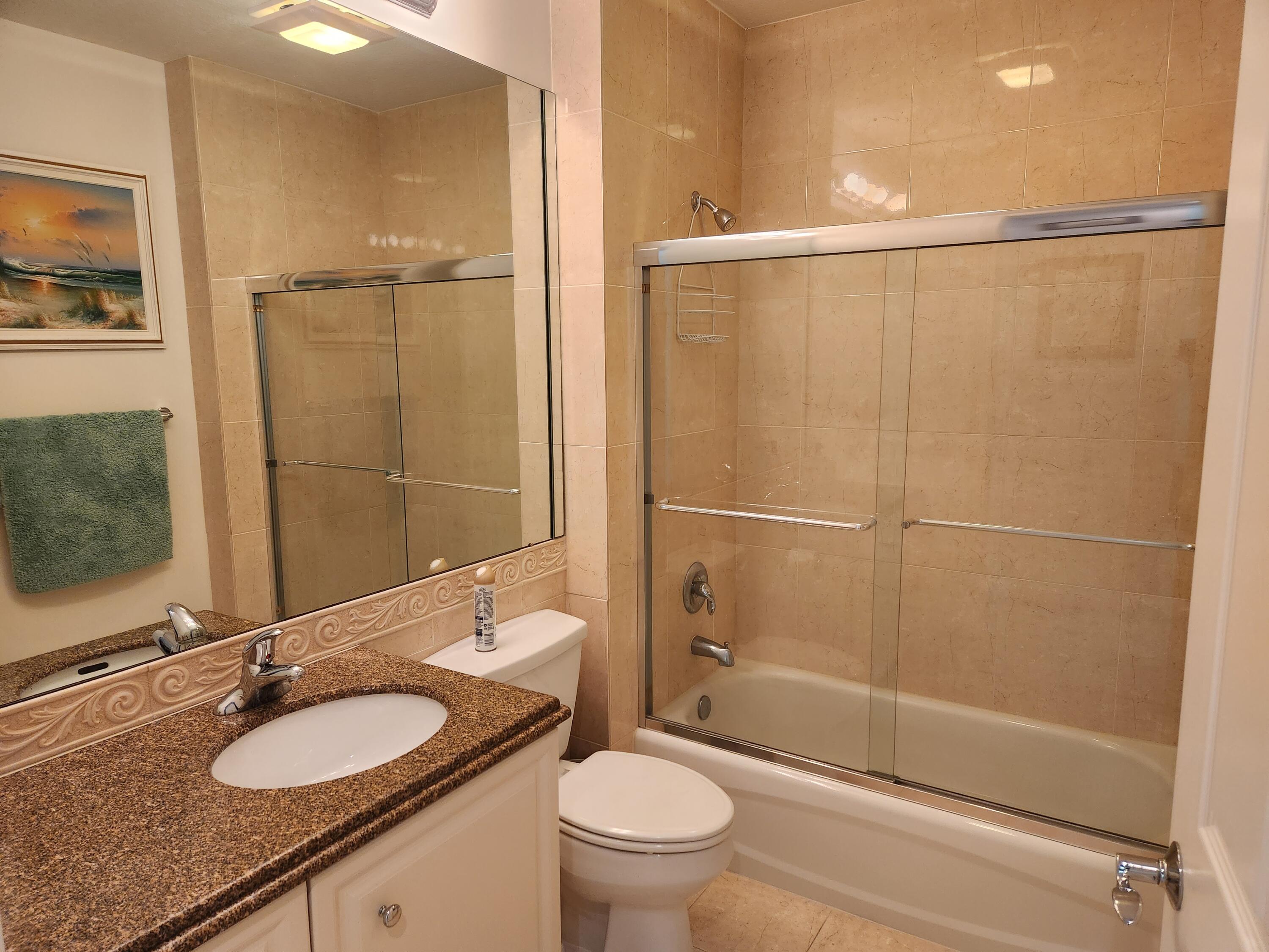 1 Harbour Isle Drive East, Unit 104 Fort Pierce, FL 34949 - Photo 24 of 28 a bathroom with a granite countertop sink toilet mirror and shower