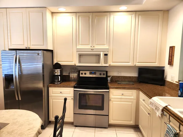 a kitchen with granite countertop a stove a sink and a refrigerator
