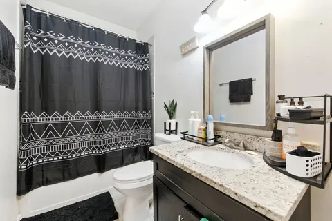 a bathroom with a granite countertop toilet sink and mirror