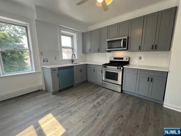 a kitchen with a sink wooden floor and stainless steel appliances