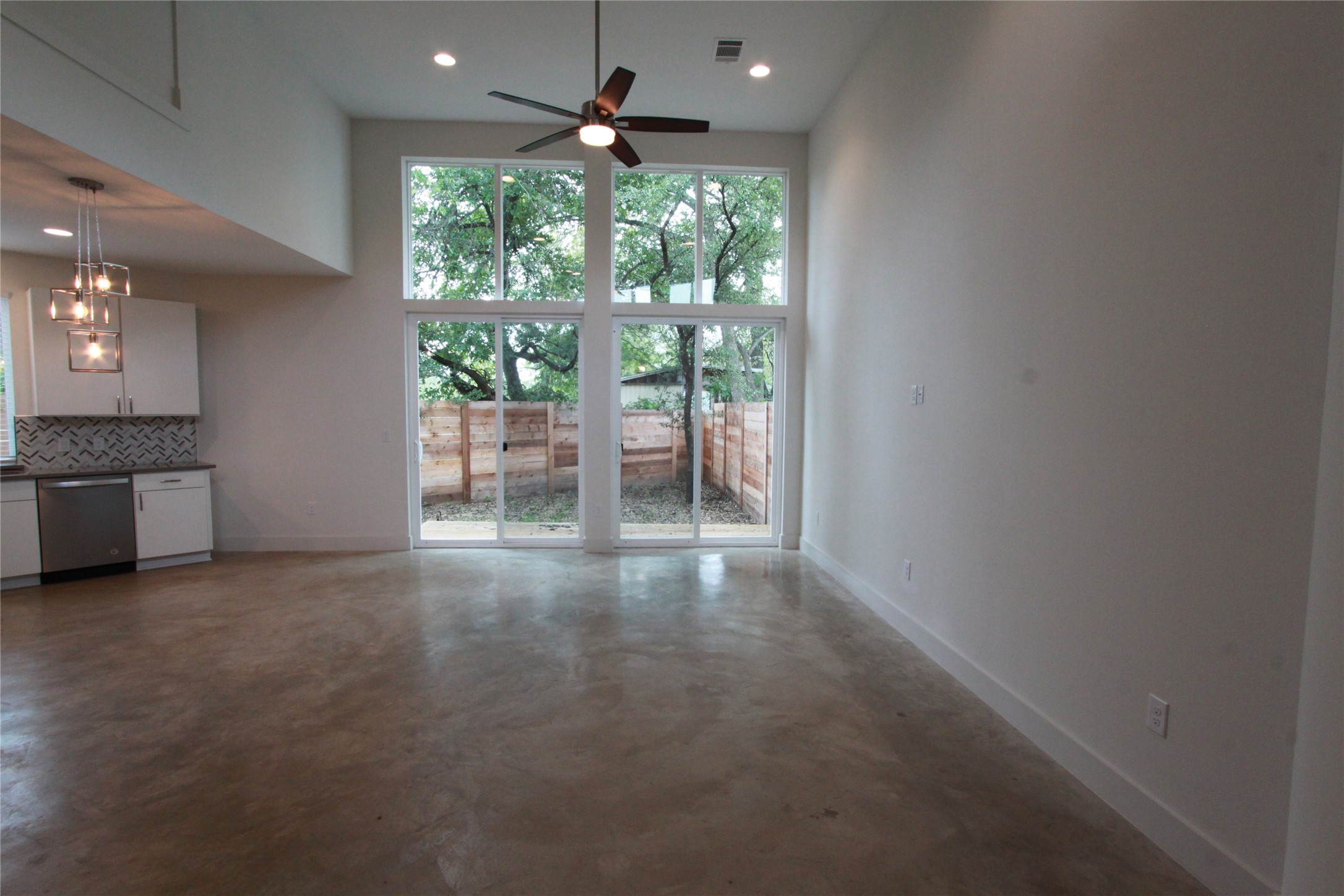1204 Cometa Street, Unit A Austin, TX 78721 - Photo 11 of 38 Unfurnished living room featuring ceiling fan, finished concrete floors, recessed lighting, and a high ceiling
