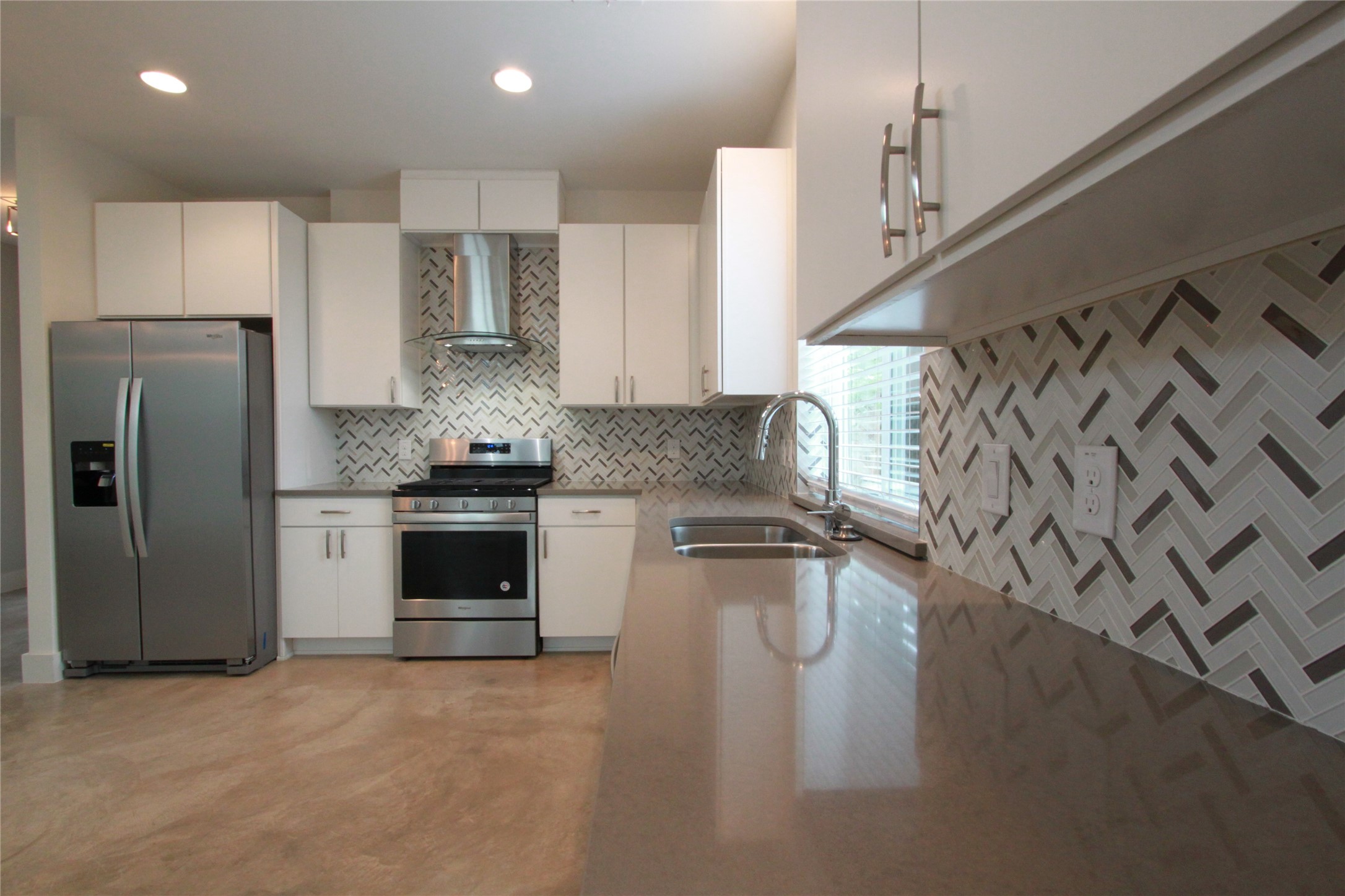 1204 Cometa Street, Unit A Austin, TX 78721 - Photo 14 of 38 Kitchen featuring stainless steel appliances, light stone counters, white cabinets, recessed lighting, and finished concrete flooring