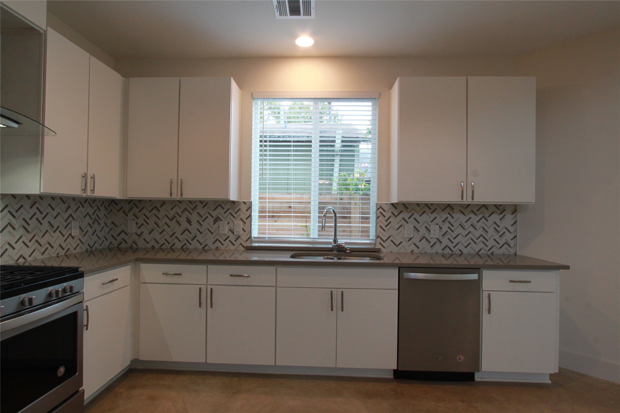 1204 Cometa Street, Unit A Austin, TX 78721 - Photo 15 of 38 Kitchen featuring white cabinets, stainless steel appliances, range hood, light stone countertops, and recessed lighting