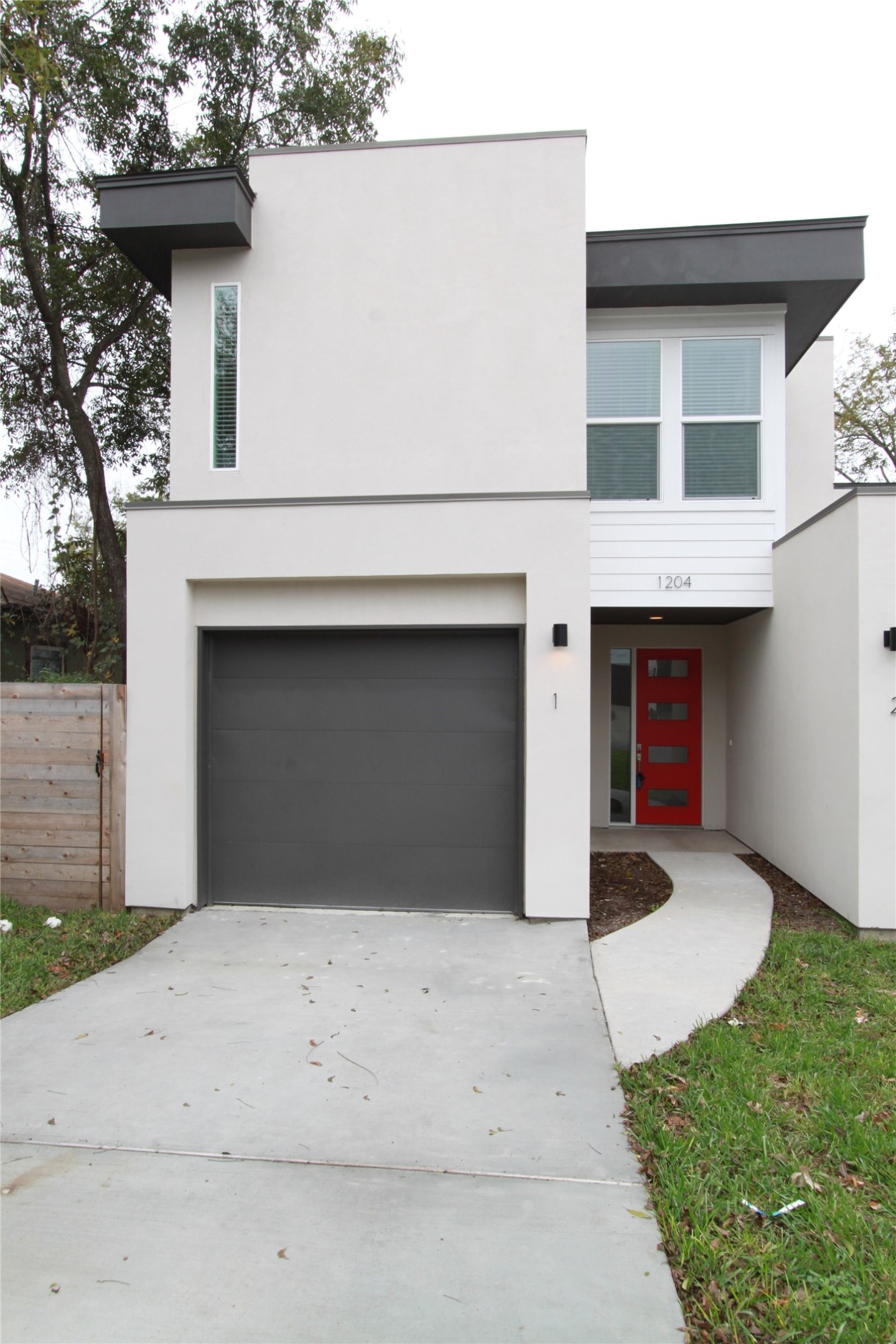 1204 Cometa Street, Unit A Austin, TX 78721 - Photo 2 of 38 Contemporary home with stucco siding, concrete driveway, and an attached garage
