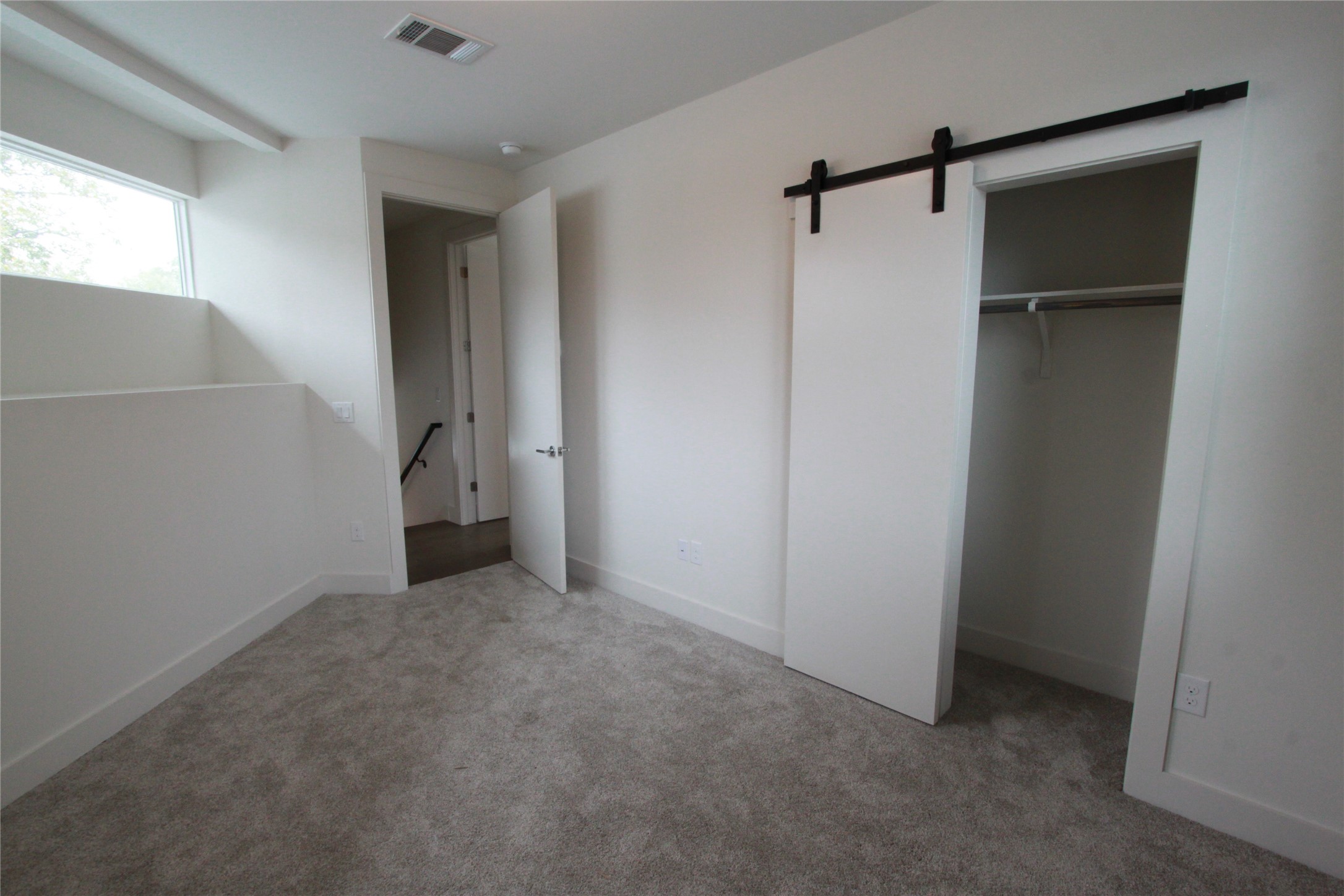 1204 Cometa Street, Unit A Austin, TX 78721 - Photo 28 of 38 Unfurnished bedroom with a barn door, light carpet, and a walk in closet