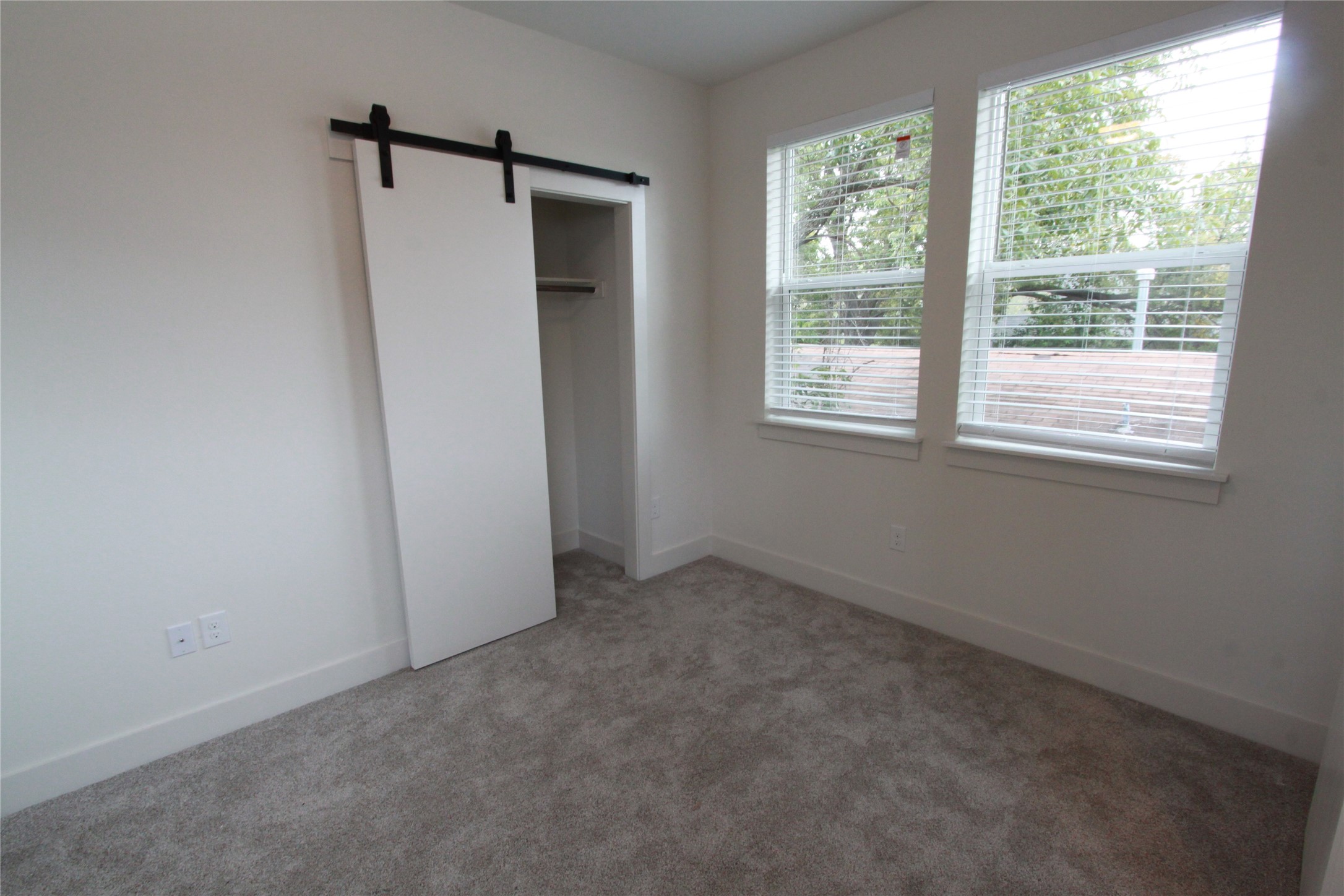 1204 Cometa Street, Unit A Austin, TX 78721 - Photo 29 of 38 Unfurnished bedroom with a barn door, light carpet, and a closet