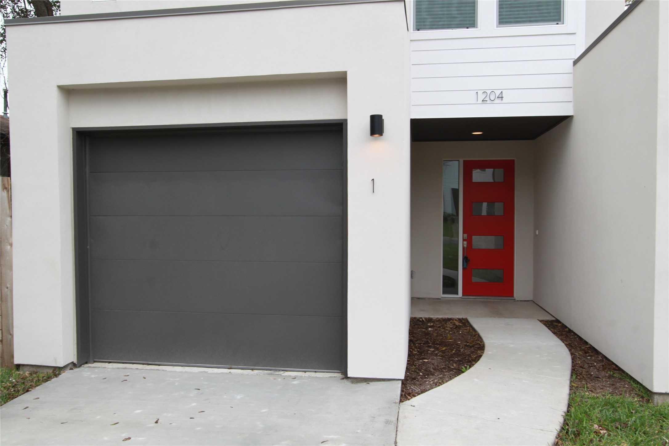 1204 Cometa Street, Unit A Austin, TX 78721 - Photo 3 of 38 Doorway to property with a garage and stucco siding