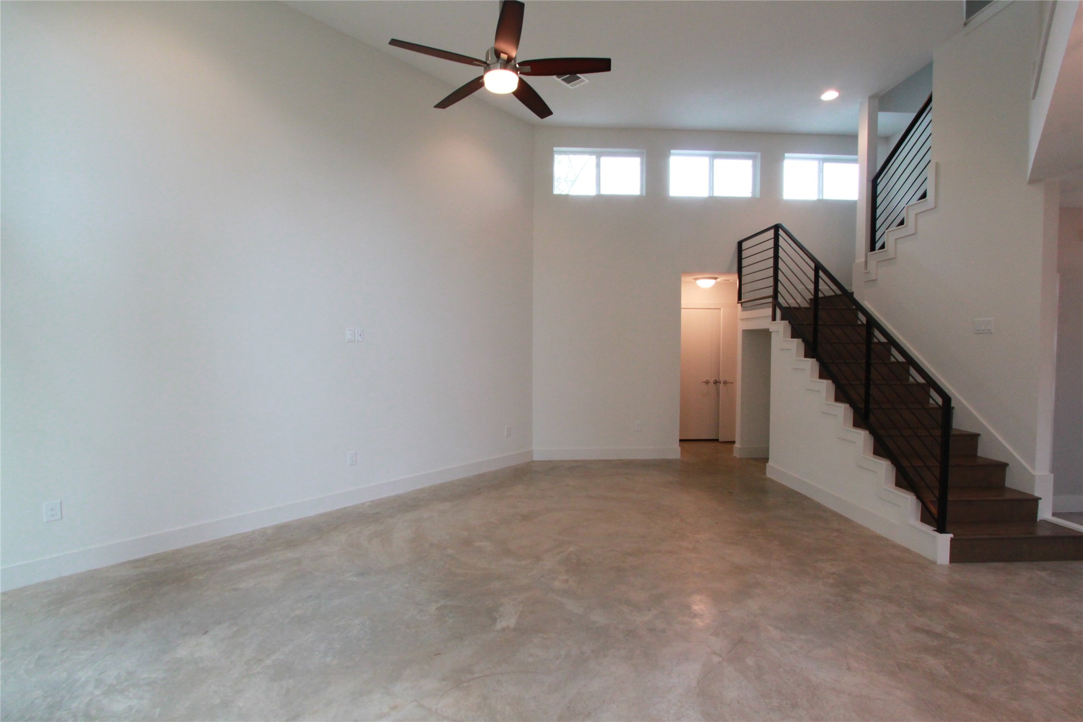 1204 Cometa Street, Unit A Austin, TX 78721 - Photo 7 of 38 Unfurnished living room featuring finished concrete floors, a ceiling fan, and a high ceiling