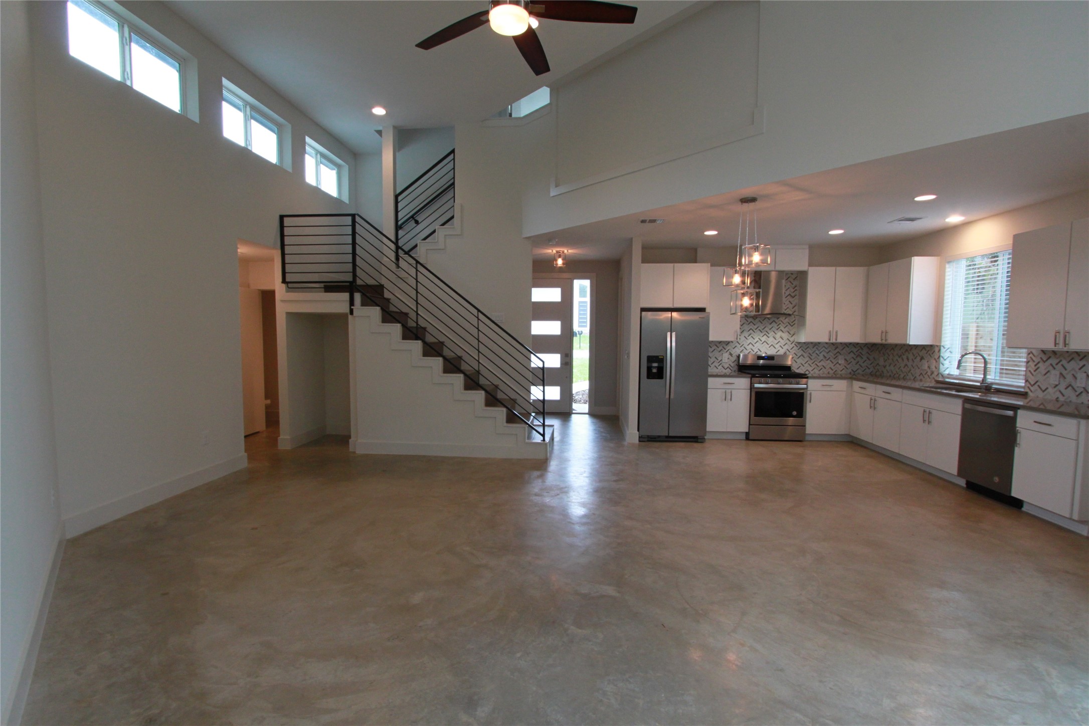 1204 Cometa Street, Unit A Austin, TX 78721 - Photo 8 of 38 Kitchen featuring white cabinets, stainless steel appliances, tasteful backsplash, a ceiling fan, and finished concrete flooring