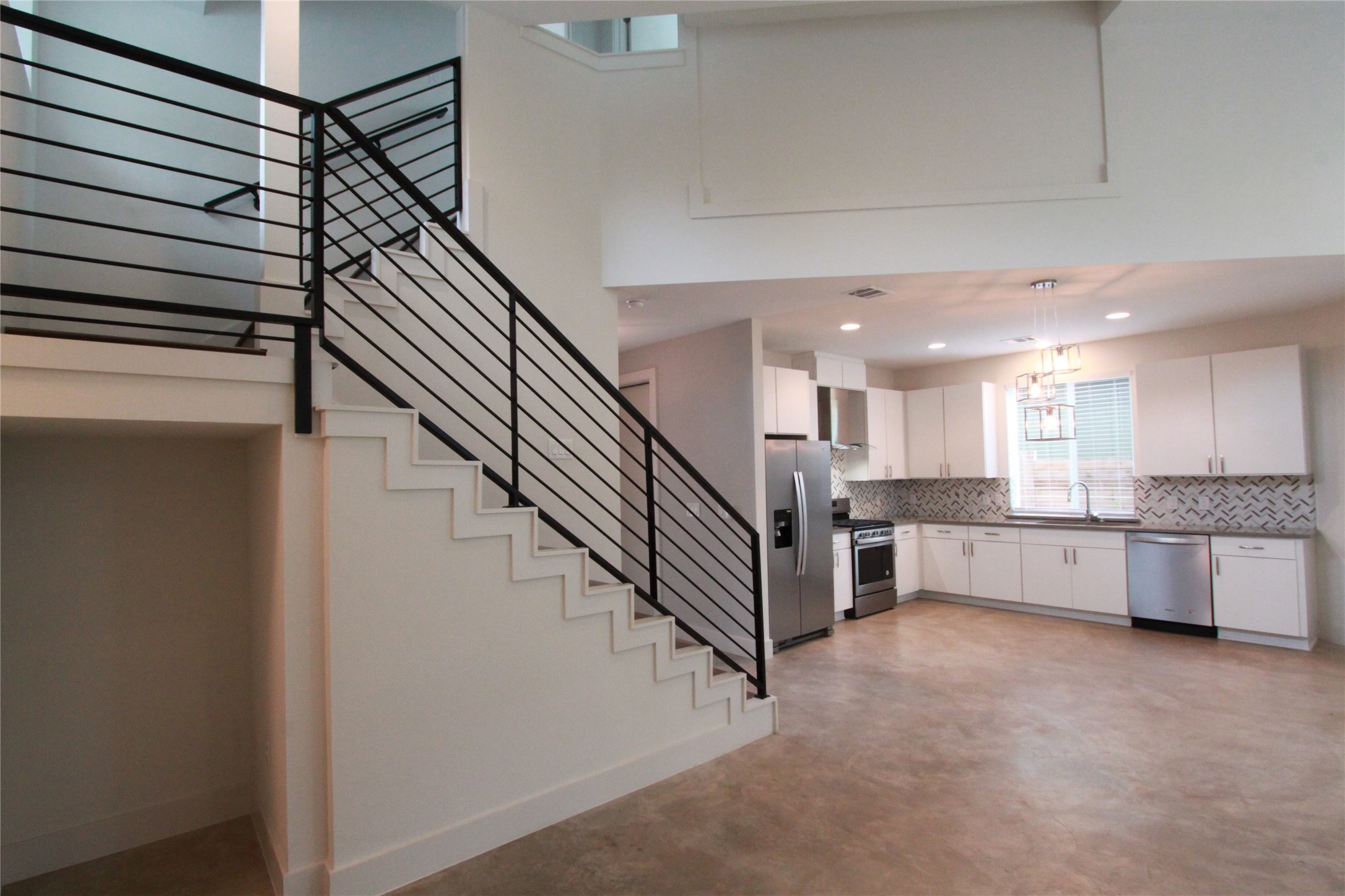 1204 Cometa Street, Unit A Austin, TX 78721 - Photo 10 of 38 Kitchen with white cabinetry, backsplash, stainless steel appliances, finished concrete flooring, and dark countertops