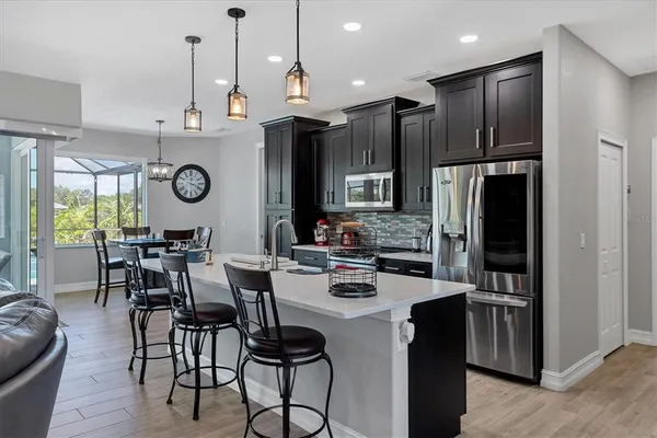 a kitchen with stainless steel appliances kitchen island granite countertop a refrigerator a stove a sink and a dining table with wooden floor