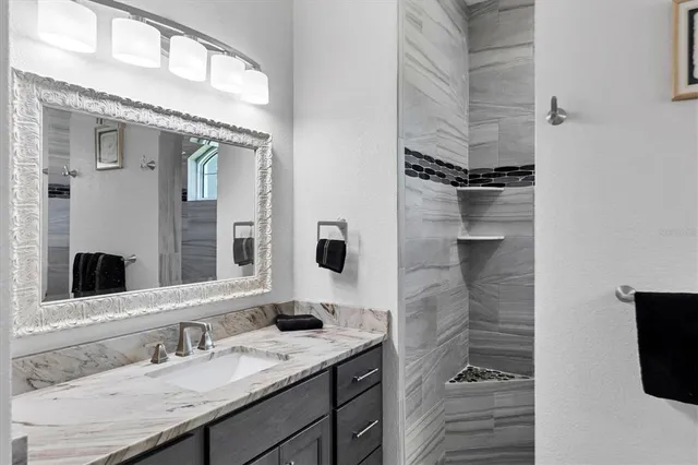a bathroom with a granite countertop sink a mirror and shower