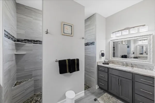 a spacious bathroom with a granite countertop sink a mirror and shower