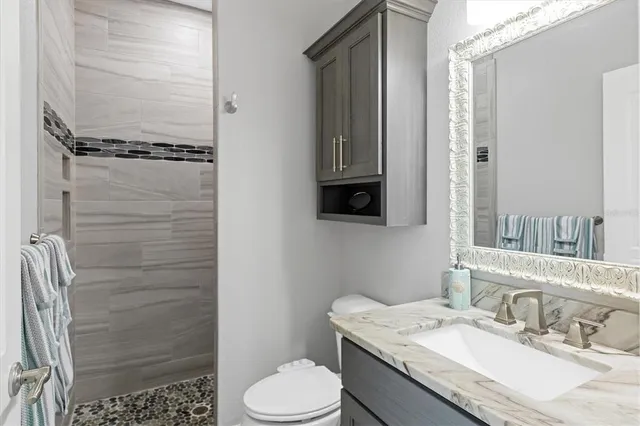 a bathroom with a granite countertop sink toilet and shower