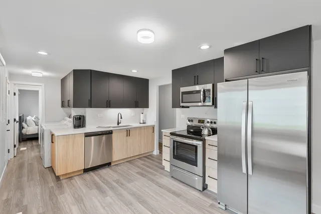 a kitchen with stainless steel appliances a refrigerator a stove a sink cabinets and wooden floor