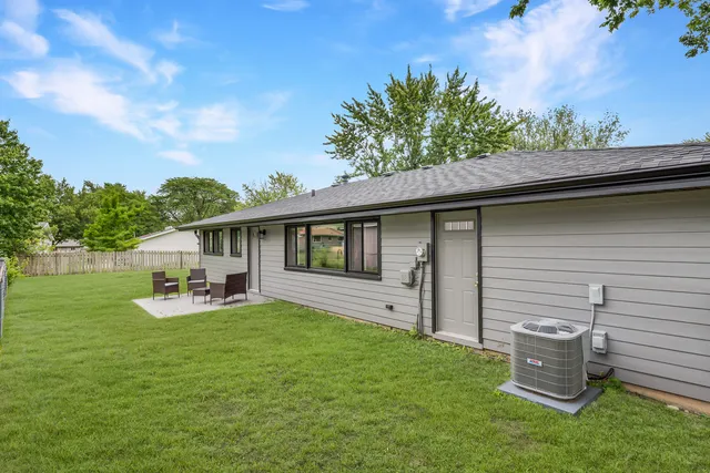 a backyard of a house with table and chairs plants and large tree