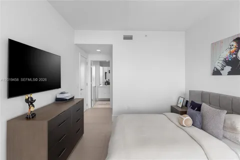 a bedroom with a bed and a flat tv screen on the dresser