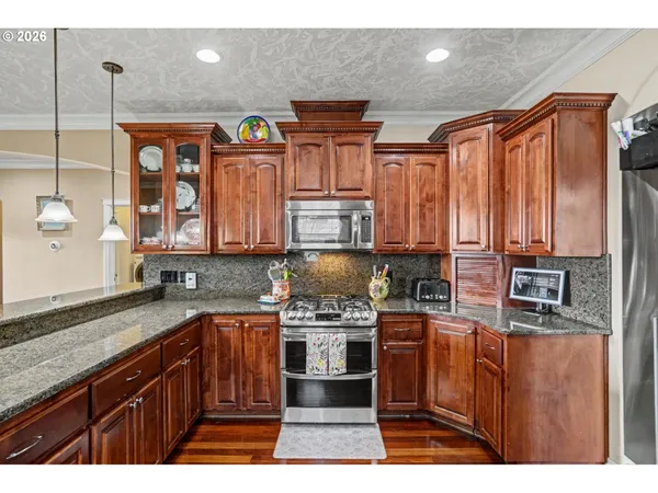 a kitchen with stainless steel appliances granite countertop a stove a sink and a microwave