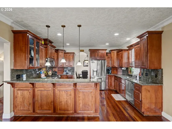 a open kitchen with stainless steel appliances granite countertop a refrigerator a stove and a wooden cabinets