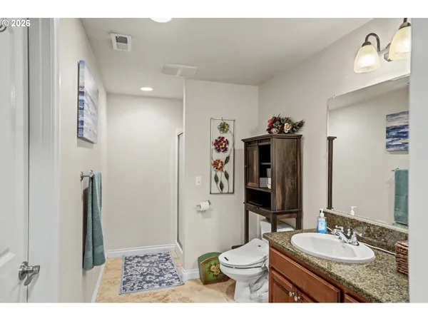 a bathroom with a granite countertop sink toilet a mirror a vanity and shower