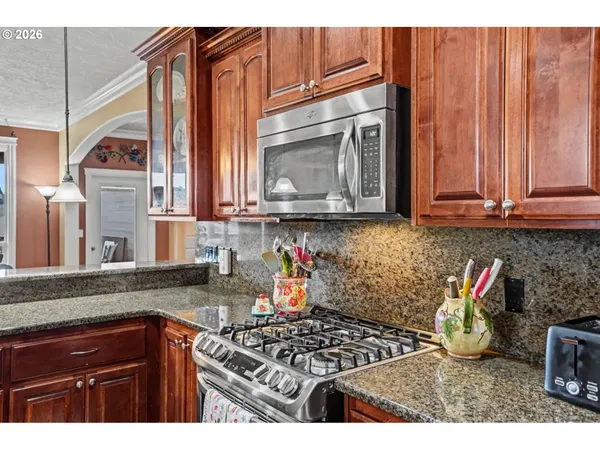 a kitchen with granite countertop a stove a sink and a microwave