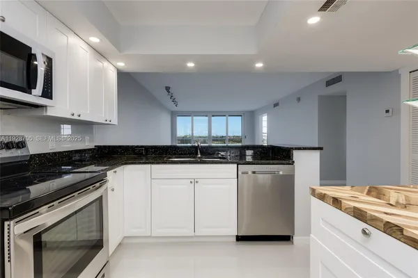 a kitchen with stainless steel appliances granite countertop a stove a sink and a microwave