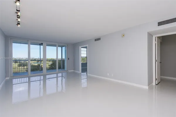 an empty room with floor to ceiling windows and chandelier