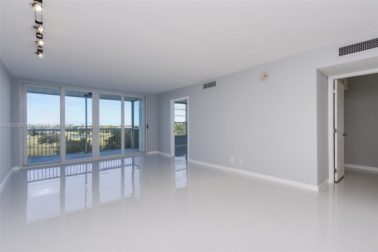 3090 North Course Drive, Unit 609 Pompano Beach, FL 33069 - Photo 6 of 36 an empty room with floor to ceiling windows and chandelier