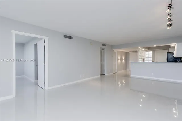 a view of a big room with wooden floor and windows