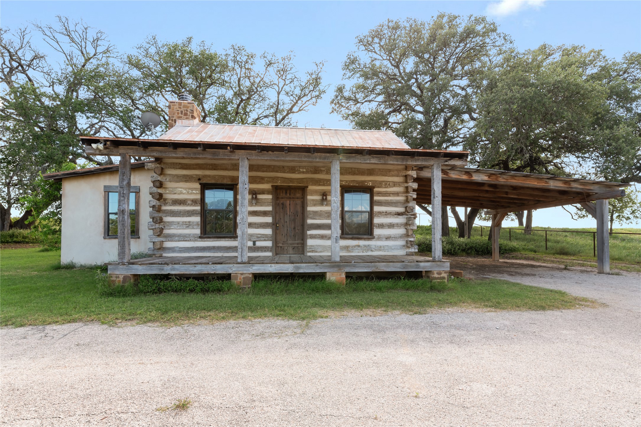 125 Hye Albert Road Hye, TX 78635 - Photo 26 of 39 Log home featuring covered porch, log siding, a chimney, a carport, and a front yard