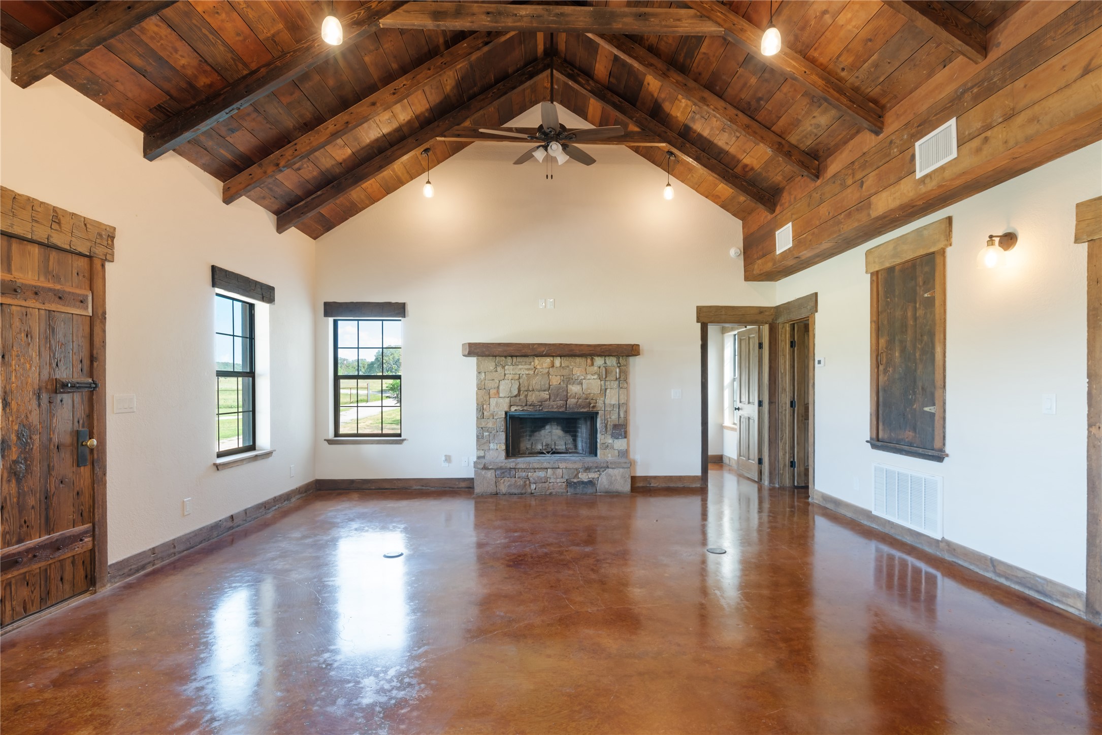 125 Hye Albert Road Hye, TX 78635 - Photo 28 of 39 Unfurnished living room with a wooden ceiling with exposed beams, high vaulted ceiling, a fireplace, finished concrete flooring, and ceiling fan