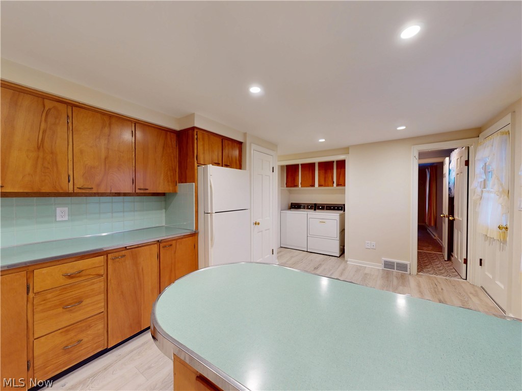 145 Overlook Road Painesville, OH 44077 - Photo 22 of 36 Kitchen with freestanding refrigerator, wood finish cabinets, washer and dryer, light countertops, and light wood-type flooring