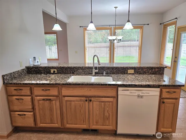 a kitchen with granite countertop a sink a window stainless steel appliances and cabinets