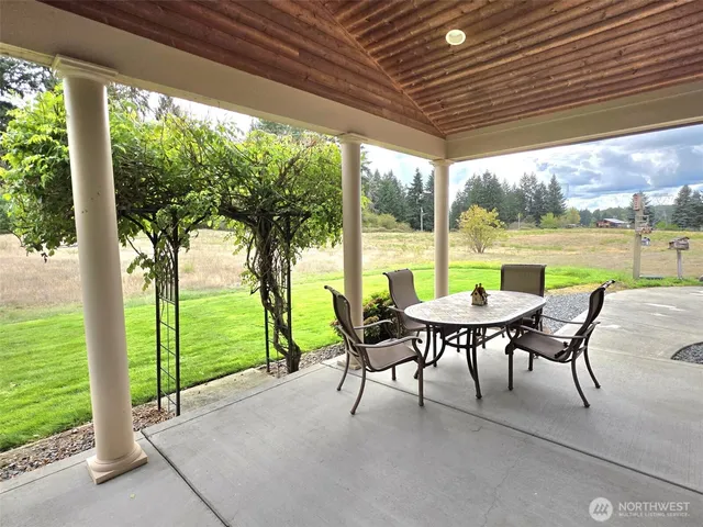 a view of a patio with table and chairs potted plants with floor to ceiling window