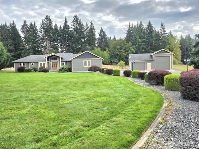 a view of a house with a big yard plants and large trees