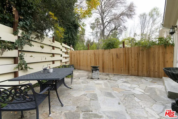 a view of backyard with table and chairs and wooden fence