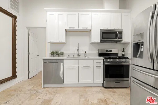 a kitchen with stainless steel appliances white cabinets a stove top oven a sink and dishwasher