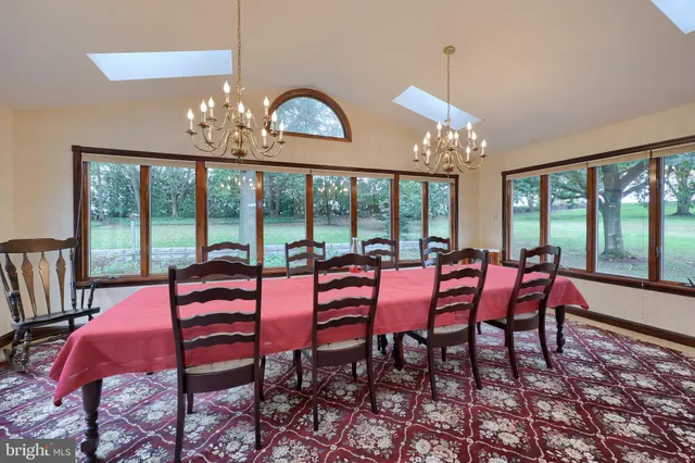 a view of a dining room with furniture a chandelier and large windows