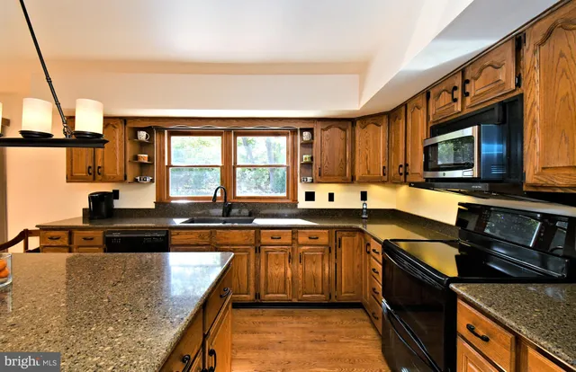 a kitchen with stainless steel appliances granite countertop a stove top oven a sink dishwasher a dining table and chairs with wooden floor