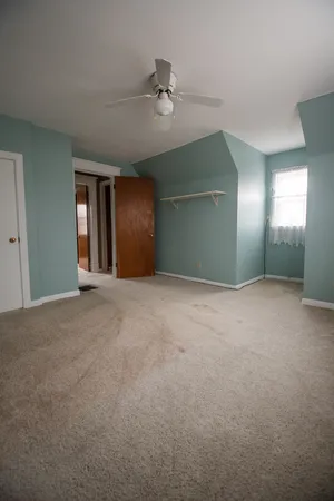 a view of an empty room with a chandelier fan
