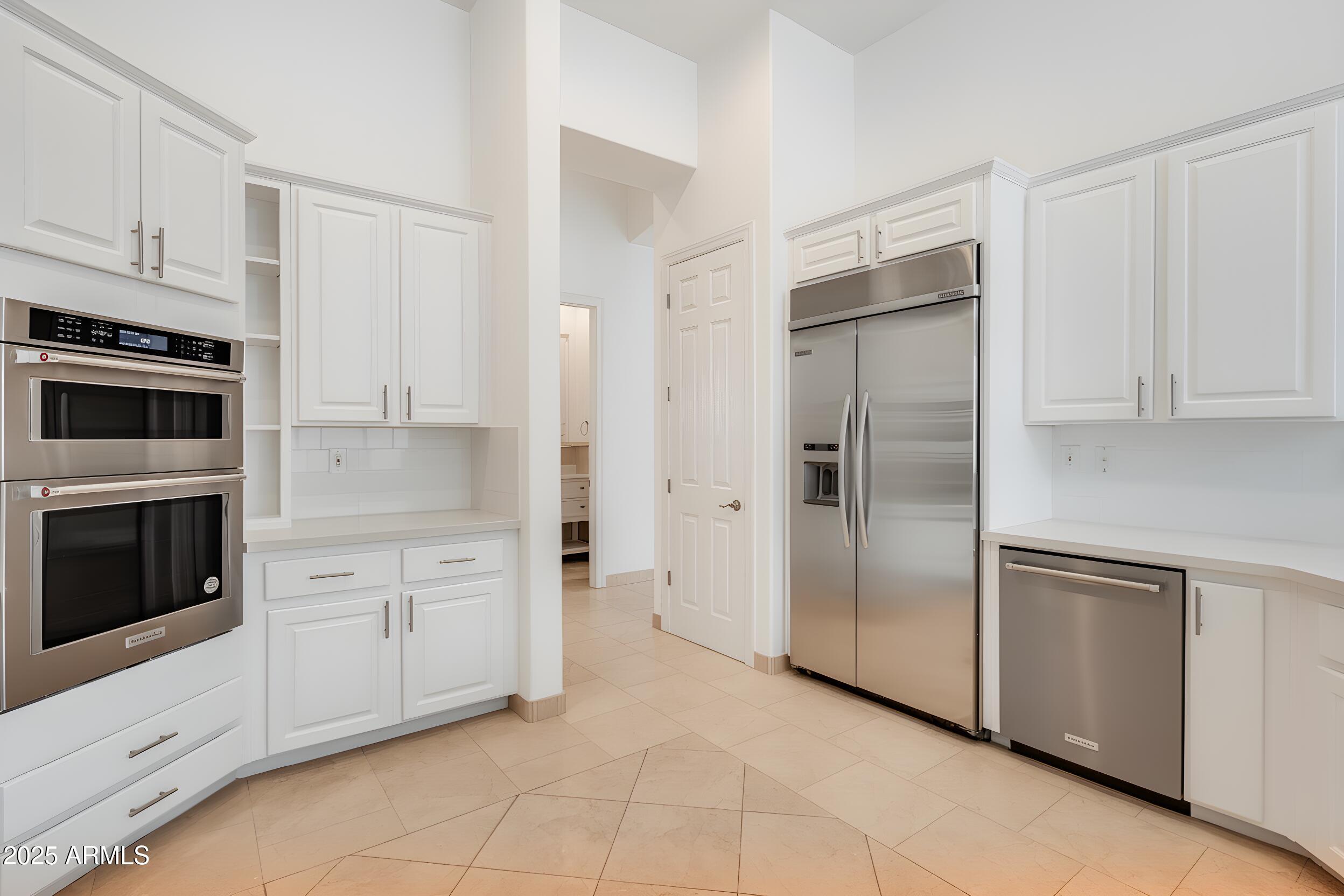 3138 West Ravina Lane Anthem, AZ 85086 - Photo 7 of 38 a kitchen with white cabinets and stainless steel appliances